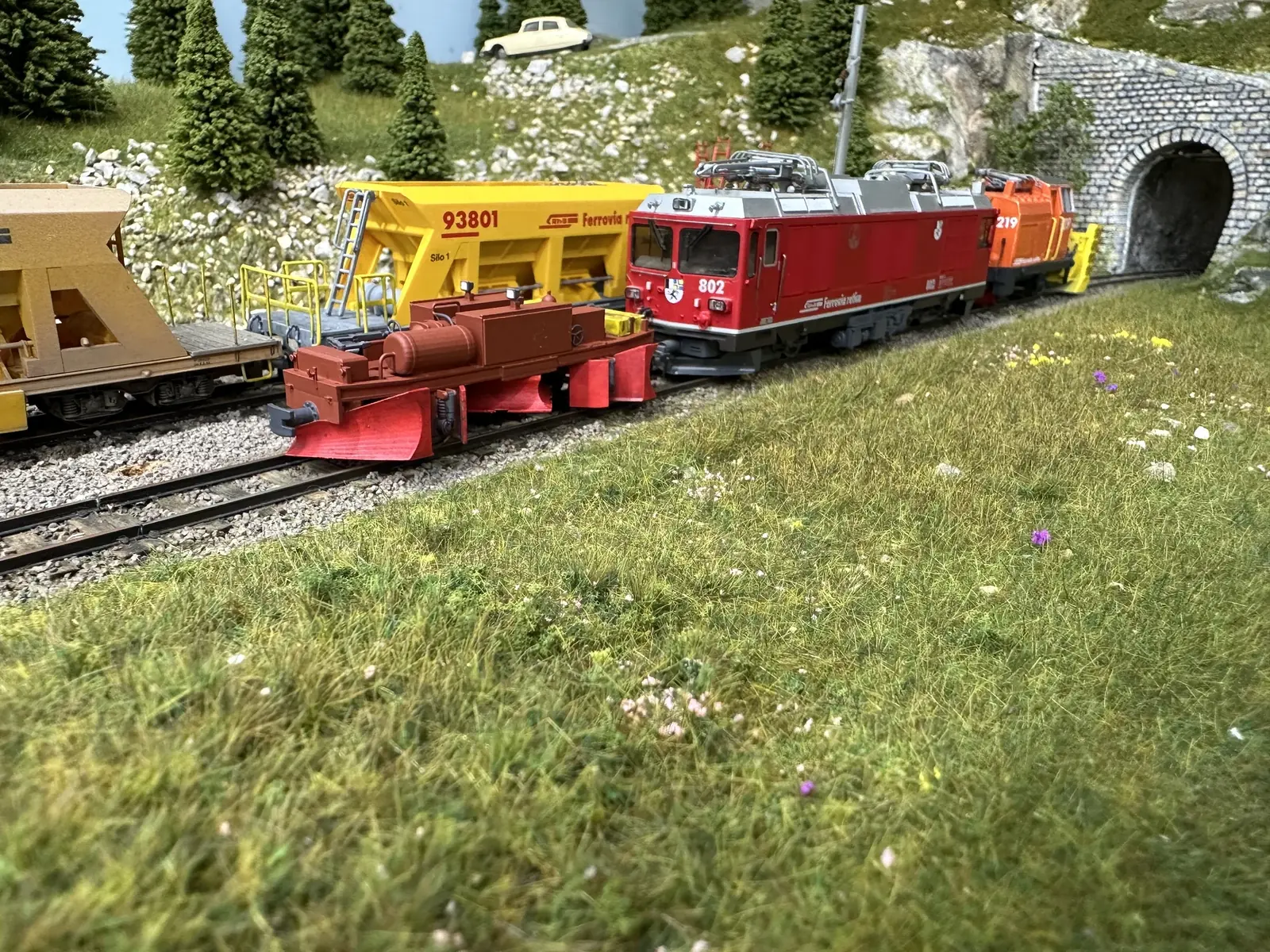 RhB snowplough and railway vehicles beside a tunnel