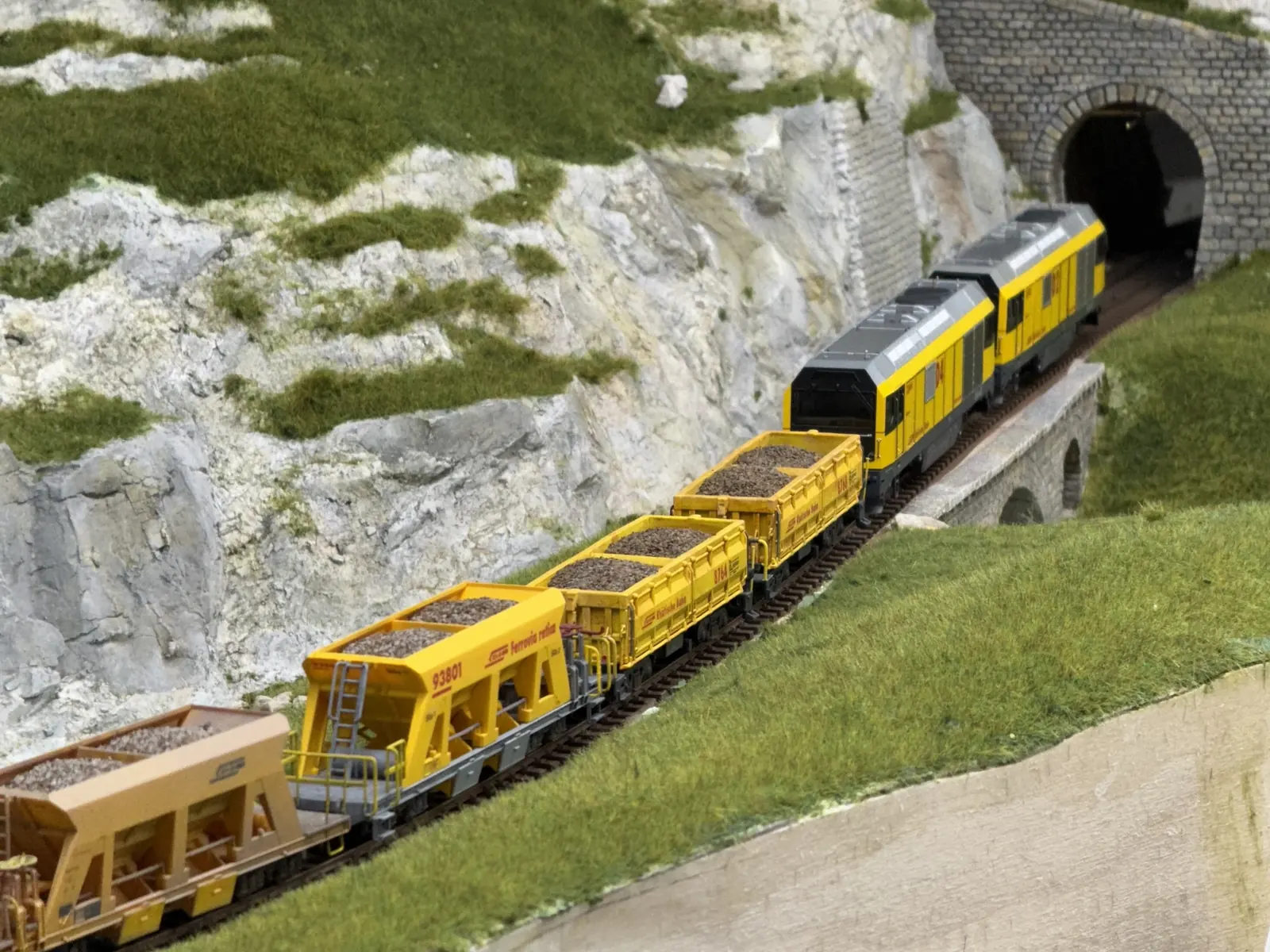 Yellow work train emerging from a tunnel