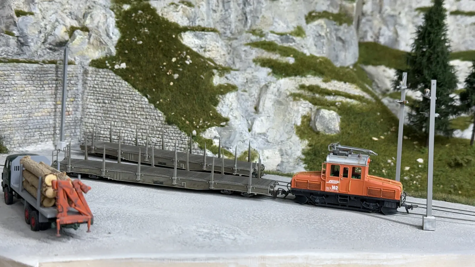 Orange service vehicle beside a long empty flatbed wagon