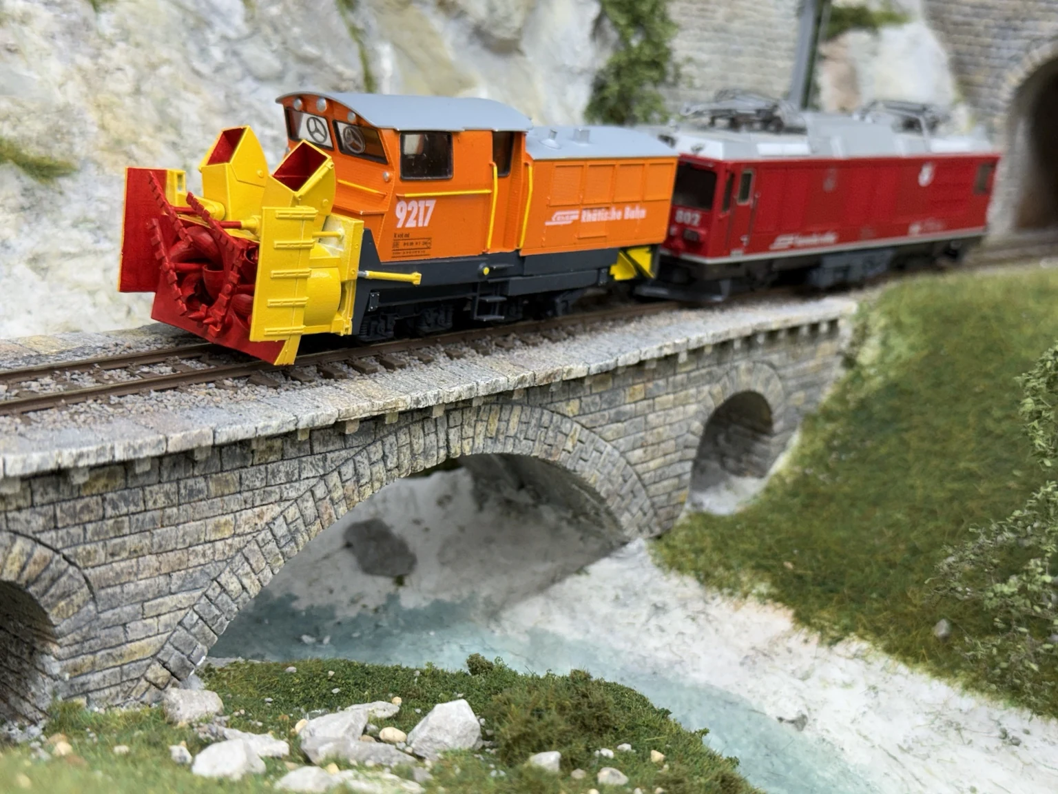 RhB Xrot mt 9217 and locomotive 802 crossing a stone bridge on the model railway